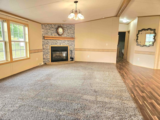 unfurnished living room featuring a stone fireplace, dark wood-type flooring, lofted ceiling with beams, an inviting chandelier, and crown molding