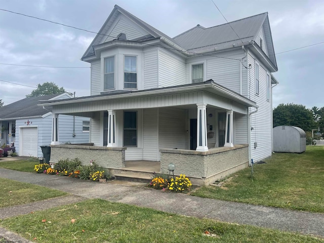 view of front of house with a garage, a front lawn, a porch, and a storage unit