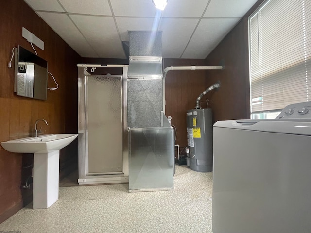 interior space featuring washer / clothes dryer, gas water heater, a drop ceiling, and wood walls