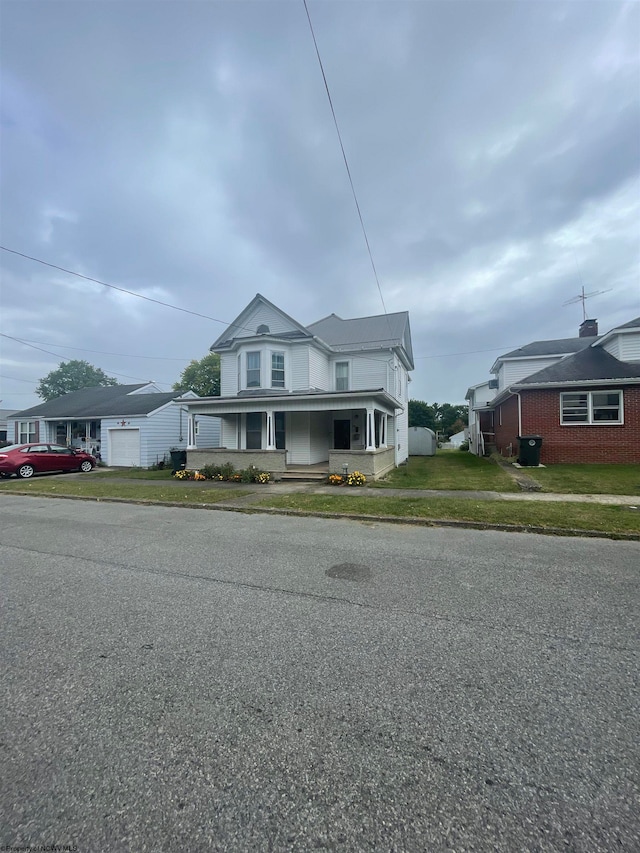 bungalow-style house featuring covered porch, a front yard, and a garage