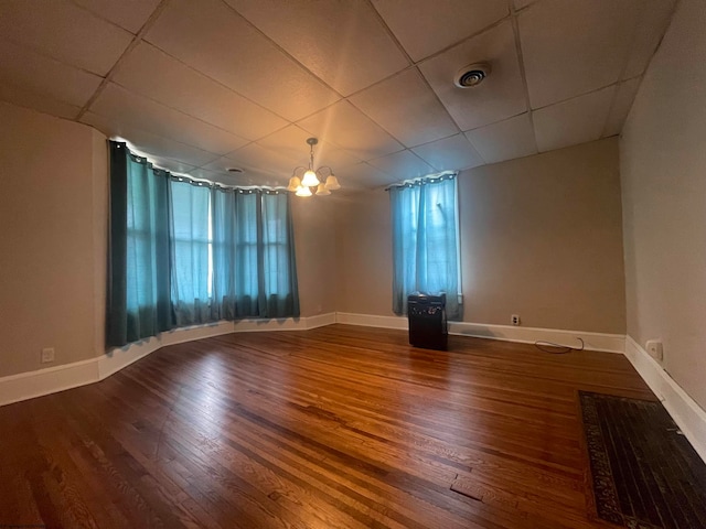 unfurnished room featuring an inviting chandelier, wood-type flooring, a healthy amount of sunlight, and a paneled ceiling