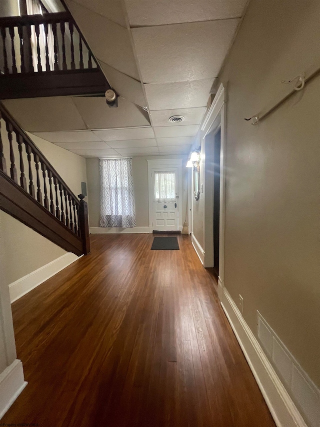 unfurnished living room featuring a drop ceiling and hardwood / wood-style floors