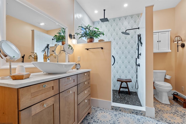 bathroom with vanity, tile patterned flooring, toilet, and tiled shower