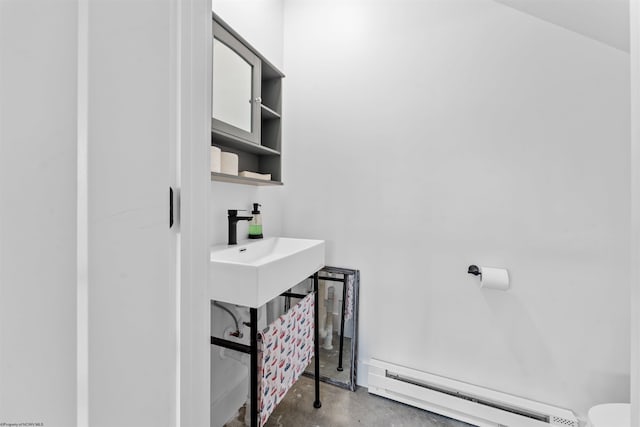 bathroom with toilet, baseboard heating, and concrete flooring