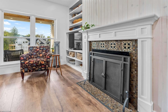 sitting room featuring wood walls, a tile fireplace, and hardwood / wood-style flooring