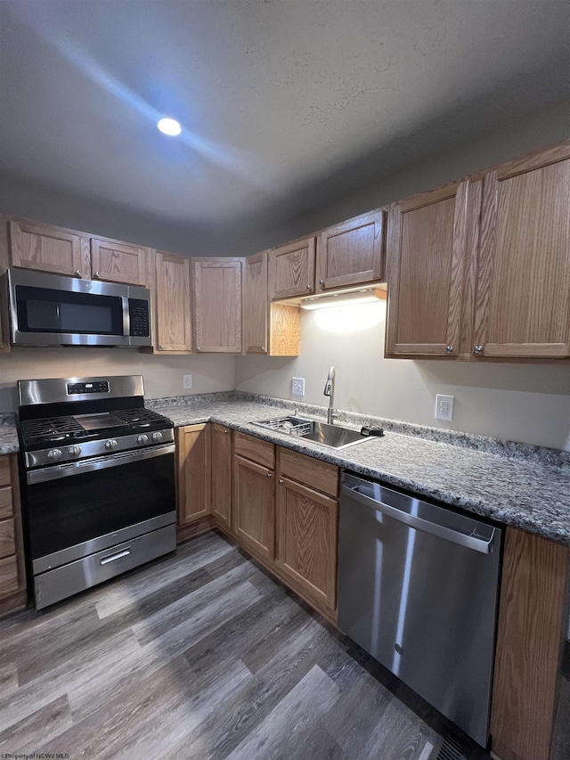 kitchen featuring appliances with stainless steel finishes, dark wood-type flooring, and a sink