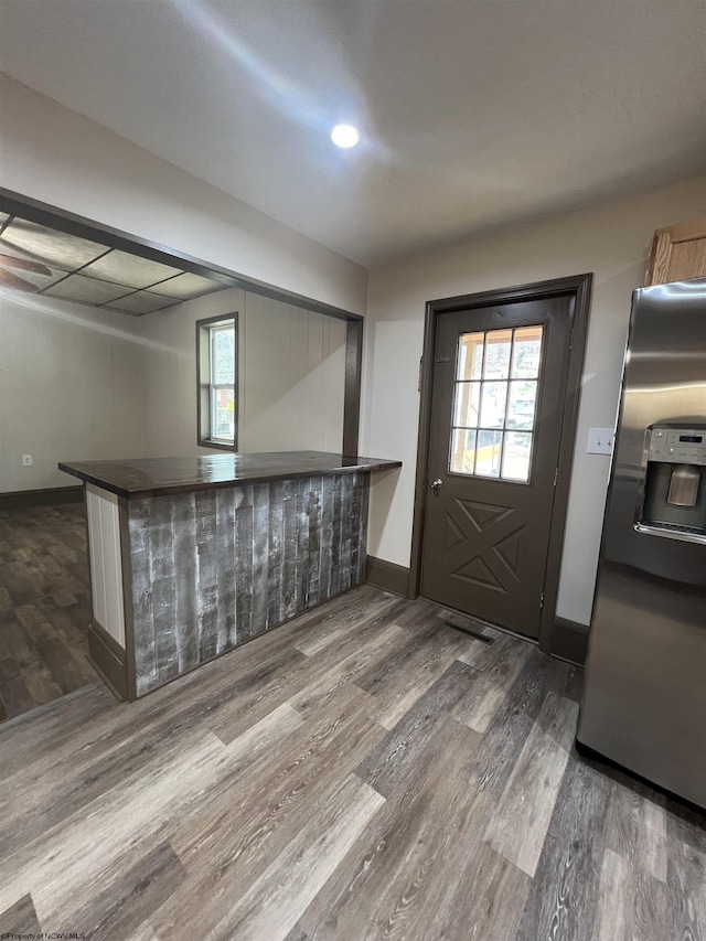 kitchen featuring dark wood-style floors, a peninsula, stainless steel refrigerator with ice dispenser, and baseboards