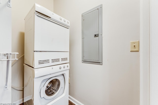 washroom featuring electric panel, hardwood / wood-style floors, and stacked washing maching and dryer