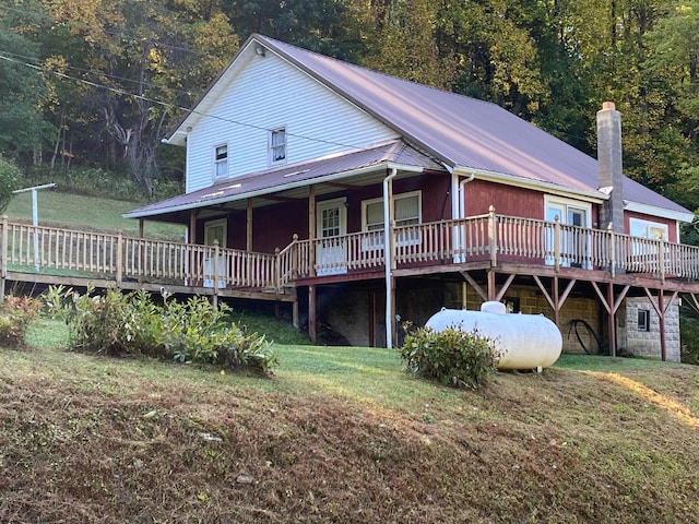 rear view of house with a wooden deck and a lawn