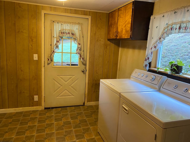 clothes washing area with wooden walls, independent washer and dryer, and cabinets