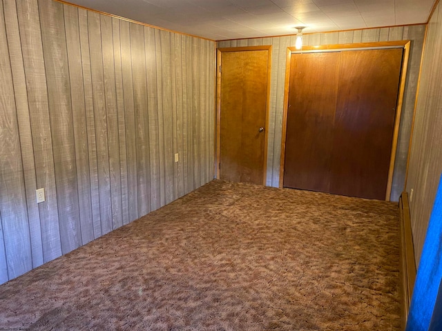 unfurnished bedroom featuring wooden walls and carpet flooring