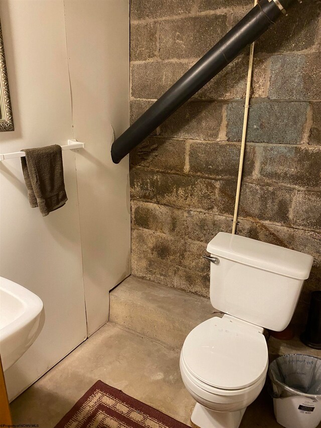 bathroom with toilet and concrete flooring