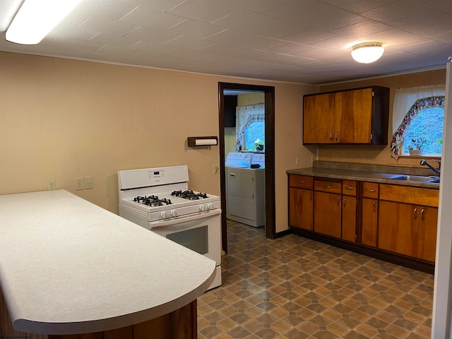 kitchen with sink, gas range gas stove, kitchen peninsula, and washer / dryer