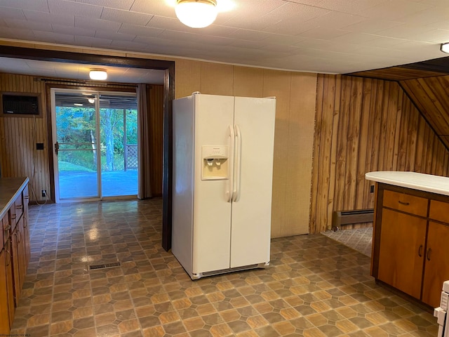 kitchen featuring wooden walls, baseboard heating, and white refrigerator with ice dispenser