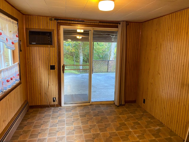 unfurnished room with a baseboard radiator, wooden walls, and a wealth of natural light