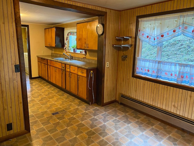 kitchen featuring wooden walls, sink, dark tile patterned flooring, and a baseboard radiator