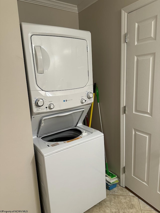 washroom with ornamental molding, light tile patterned floors, and stacked washer and clothes dryer