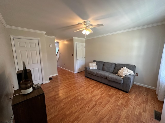 living room featuring ceiling fan, light wood-type flooring, and crown molding