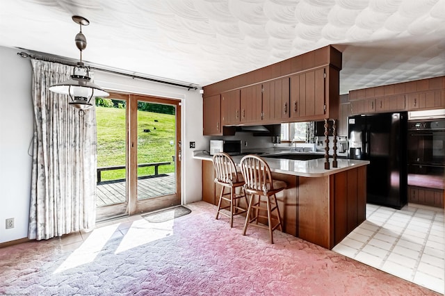 kitchen with pendant lighting, sink, a breakfast bar area, kitchen peninsula, and black appliances