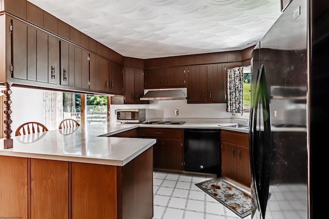 kitchen with dark brown cabinets, black appliances, kitchen peninsula, and sink