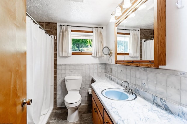 bathroom with tile walls, a textured ceiling, a shower with curtain, vanity, and toilet