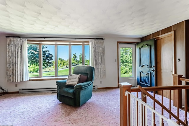 sitting room featuring a baseboard heating unit, wood walls, and carpet flooring