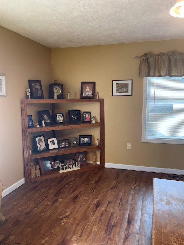 interior space with a textured ceiling and dark hardwood / wood-style floors