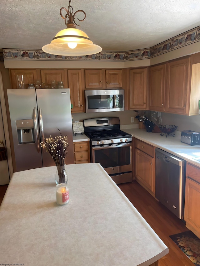 kitchen featuring decorative light fixtures, a textured ceiling, stainless steel appliances, and dark hardwood / wood-style floors