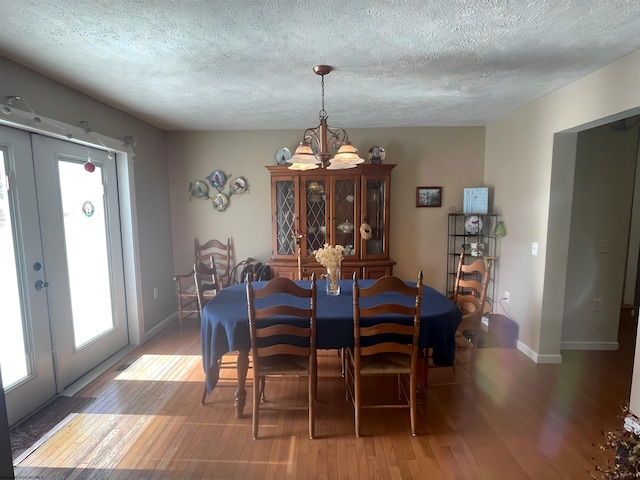 dining area featuring french doors, hardwood / wood-style flooring, a chandelier, and a textured ceiling