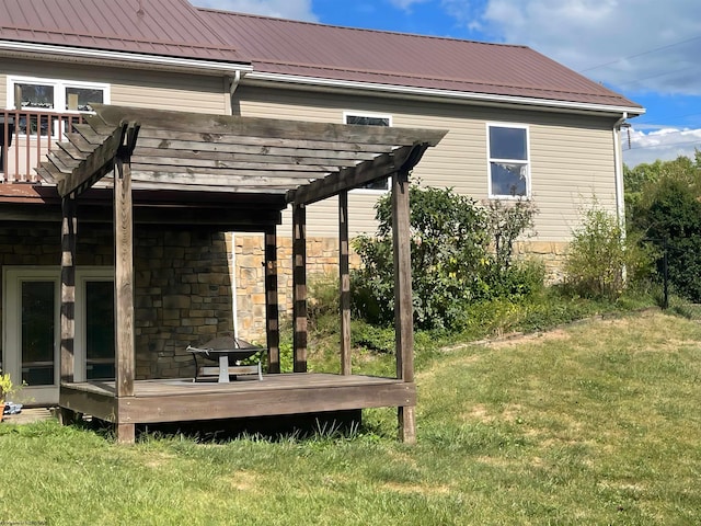 rear view of property with a wooden deck, a pergola, and a lawn