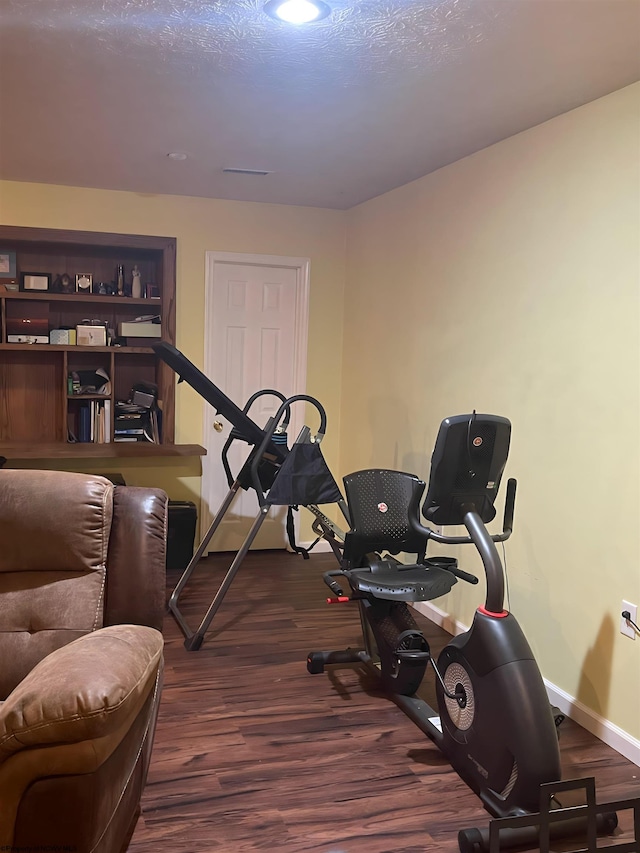 exercise room featuring a textured ceiling and dark hardwood / wood-style flooring