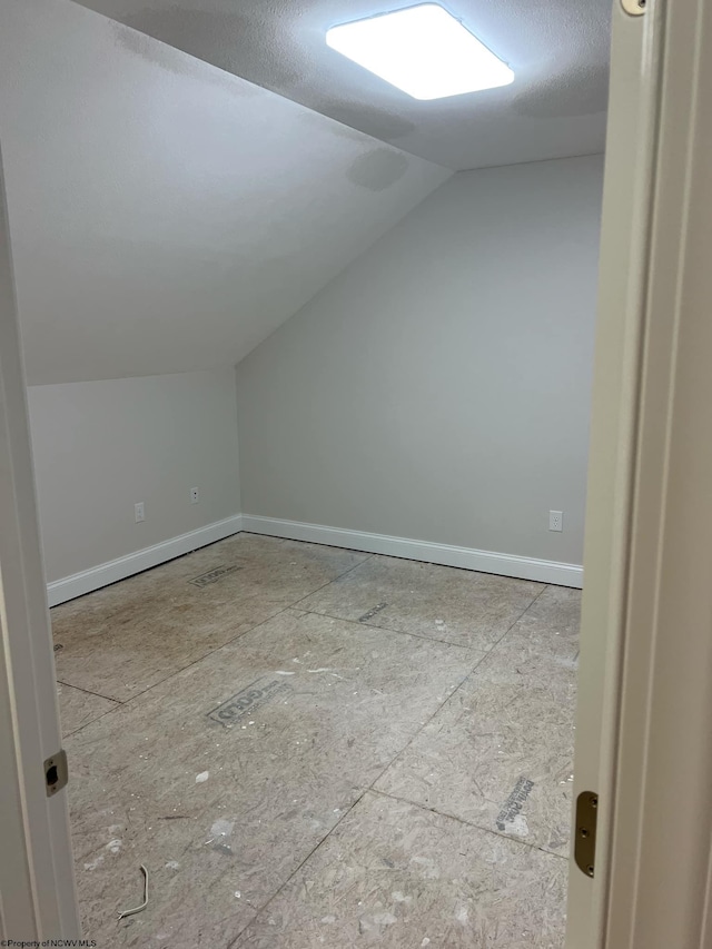 additional living space with a textured ceiling and lofted ceiling