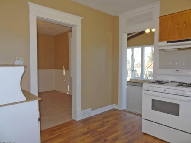 kitchen with light wood-type flooring, white gas range, and decorative backsplash