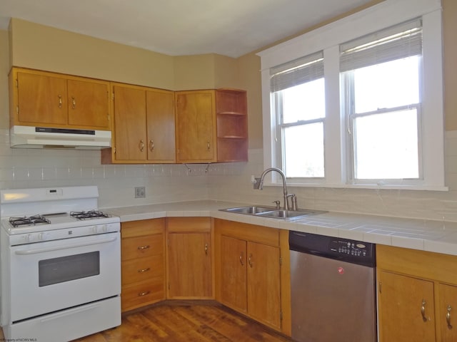 kitchen with wood-type flooring, gas range gas stove, sink, tile countertops, and stainless steel dishwasher