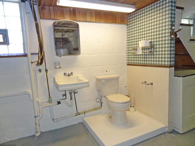 bathroom featuring toilet, sink, and concrete flooring