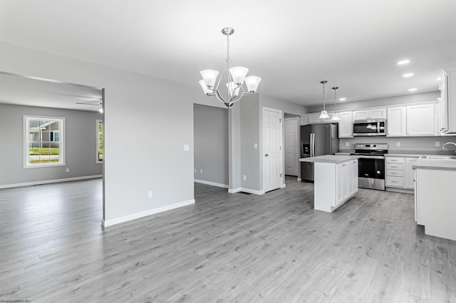 kitchen with pendant lighting, white cabinets, appliances with stainless steel finishes, a center island, and light wood-type flooring