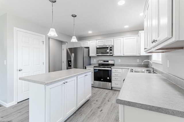 kitchen featuring a center island, sink, white cabinets, appliances with stainless steel finishes, and decorative light fixtures