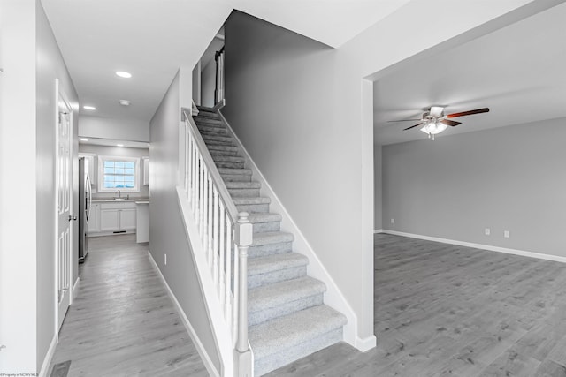 stairs featuring ceiling fan, hardwood / wood-style floors, and sink