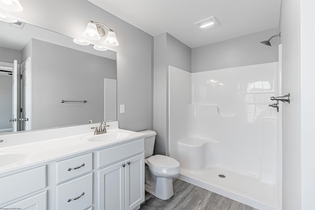 bathroom with wood-type flooring, a shower, vanity, and toilet