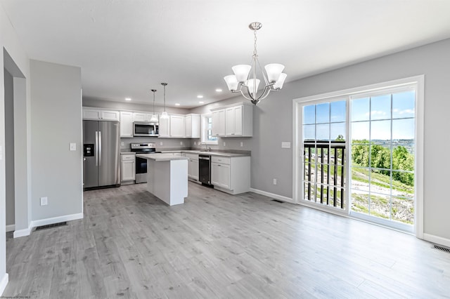 kitchen featuring appliances with stainless steel finishes, a kitchen island, pendant lighting, light hardwood / wood-style flooring, and a notable chandelier