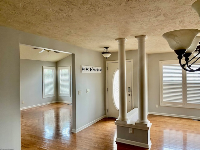 entryway featuring light hardwood / wood-style flooring, decorative columns, and a textured ceiling