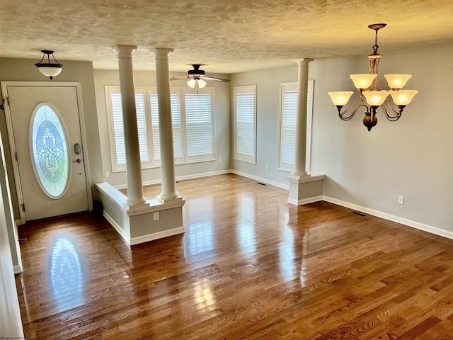 foyer entrance with wood finished floors, baseboards, ceiling fan with notable chandelier, and decorative columns