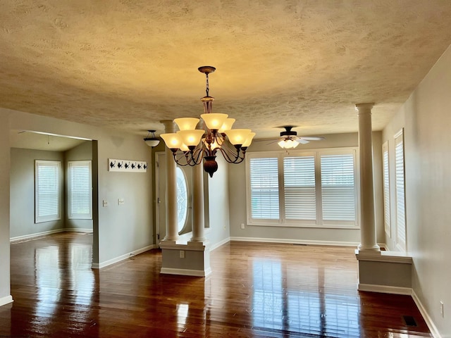 unfurnished dining area featuring hardwood / wood-style floors, ornate columns, a wealth of natural light, and a textured ceiling