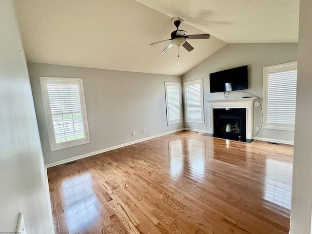 unfurnished living room featuring a fireplace with flush hearth, visible vents, ceiling fan, vaulted ceiling, and wood finished floors