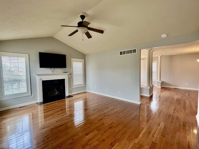 unfurnished living room featuring a fireplace with flush hearth, ceiling fan, decorative columns, visible vents, and lofted ceiling
