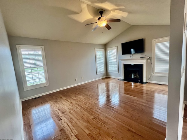 unfurnished living room featuring ceiling fan, wood finished floors, visible vents, baseboards, and lofted ceiling