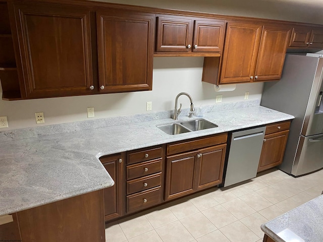 kitchen with light stone countertops, stainless steel appliances, light tile patterned floors, and sink