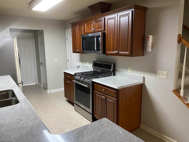 kitchen with light tile patterned floors, stainless steel appliances, and light stone counters