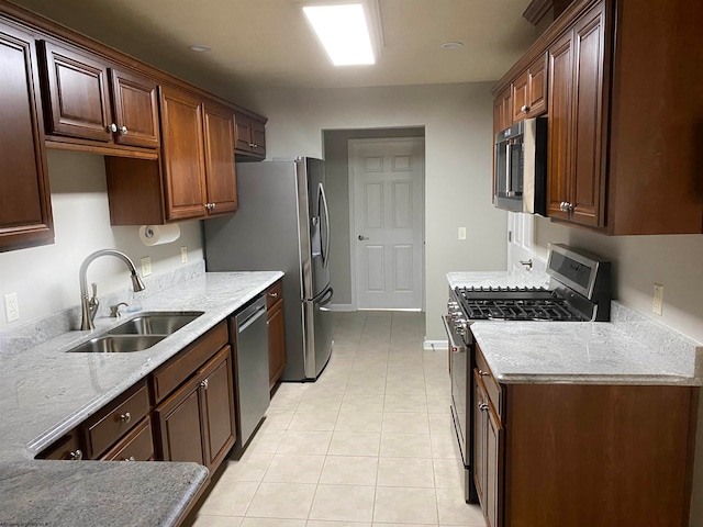 kitchen with light tile patterned floors, appliances with stainless steel finishes, sink, and light stone countertops