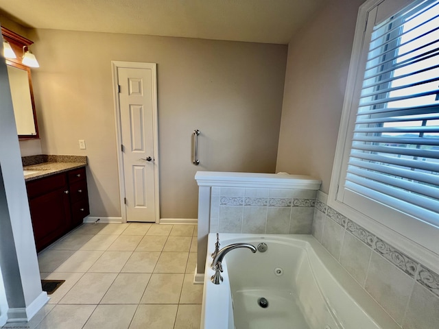 bathroom featuring a tub with jets, a wealth of natural light, tile patterned flooring, and vanity